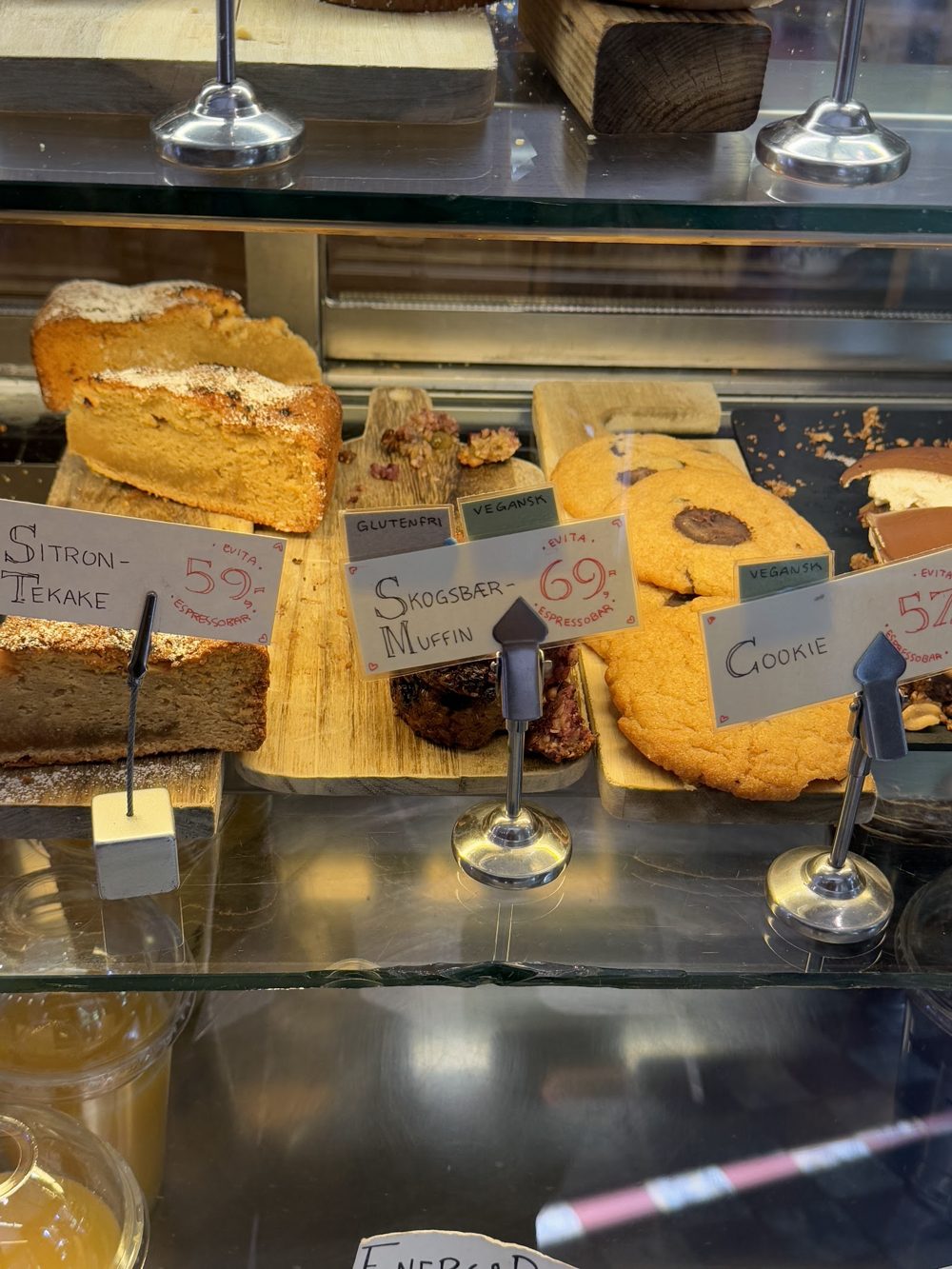 Disken hos Evita med sitrontekake, skogsbærmuffin og cookies på håndskrevne prisskilt